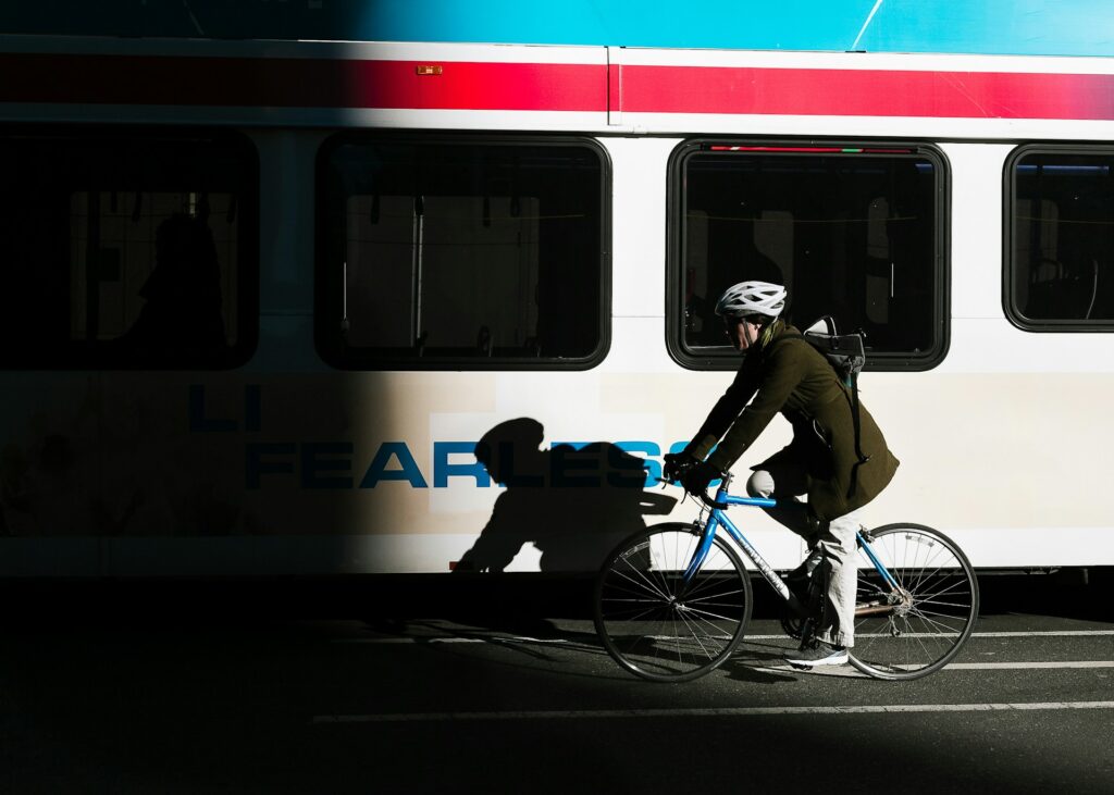 hotos/person-ride-on-city-bike-on-asphalt-road-beside-white-bus-KHrGmSkE6rE