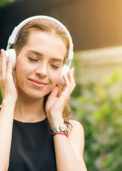 woman-wearing-black-sleeveless-dress-holding-white-headphone-at-daytime-1001850/