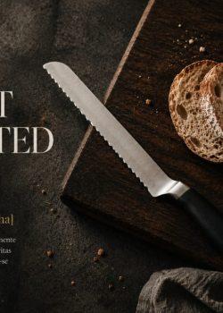 Offset serrated knife sobre uma tábua de madeira escura com pão rústico fatiado, em composição editorial de cozinha.