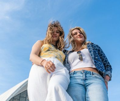 two-women-standing-against-a-bright-blue-sky-OG96N3wxoVg