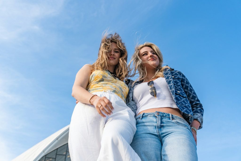 two-women-standing-against-a-bright-blue-sky-OG96N3wxoVg